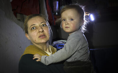 A woman holds her child as she speaks to a photographer in the basement of a building damaged during a fighting used as a bomb shelter in Mariupol, on the territory which is now under the Government of the Donetsk People's Republic control, April 8, 2022. (AP Photo/Alexei Alexandrov)