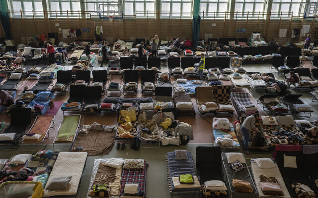 People who fled the war in Ukraine rest inside an indoor sports stadium being used as a refugee center, in the village of Medyka, a border crossing between Poland and Ukraine, on March 15, 2022. (AP Photo/Petros Giannakouris, File)
