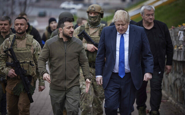 In this image provided by the Ukrainian Presidential Press Office, Ukrainian President Volodymyr Zelensky, center left, and Britain's Prime Minister Boris Johnson, center right, walk past a memorial for Heavenly Hundred, near Independence Square in Kyiv, Ukraine,  on April 9, 2022. (Ukrainian Presidential Press Office via AP)