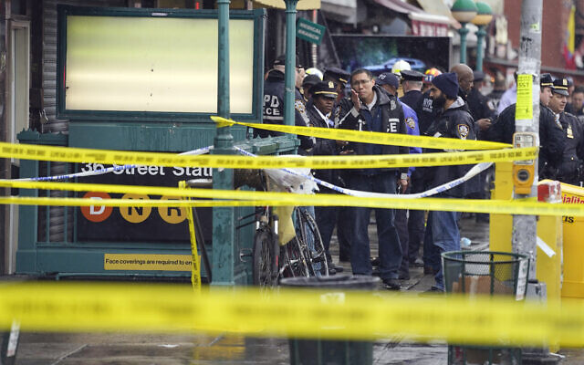 New York City Police Department personnel gather at the entrance to a subway stop in the Brooklyn borough of New York, April 12, 2022. (AP Photo/John Minchillo)