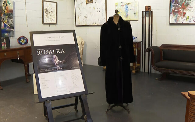 In this image from video, a black mink fur coat, right, and a signed opera poster belonging to the late Justice Ruth Bader Ginsburg, are seen inside Potomack Company Auctions in Alexandria, VA, on Monday, April 11, 2022.  (AP Photo/Nathan Ellgren)