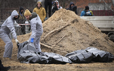 Men wearing protective gear exhume the bodies of civilians killed during the Russian occupation in Bucha, in the outskirts of Kyiv, Ukraine, on April 13, 2022. (AP Photo/Efrem Lukatsky)