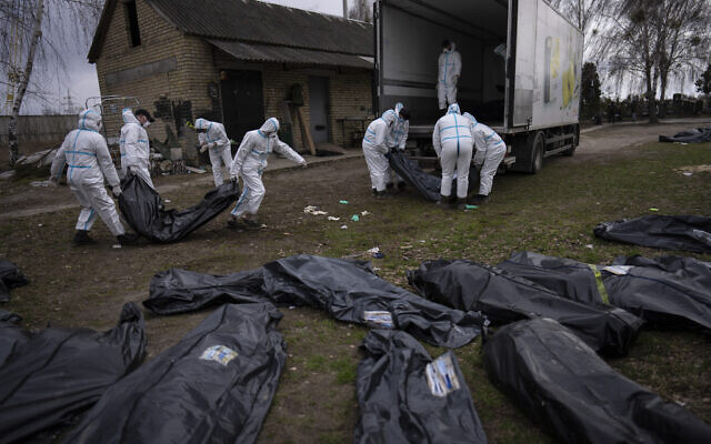 Volunteers load bodies of civilians killed in Bucha onto a truck to be taken to a morgue for investigation, in the outskirts of Kyiv, Ukraine, on April 12, 2022. (AP Photo/Rodrigo Abd)