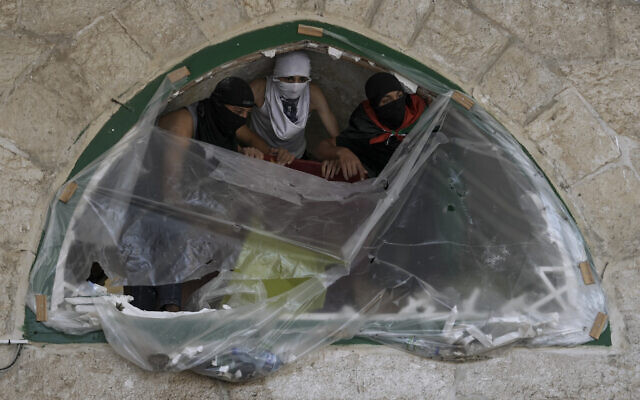 Masked Palestinians take positions during clashes with Israeli security forces at the Temple Mount in Jerusalem's Old City, April 15, 2022. (AP Photo/Mahmoud Illean)