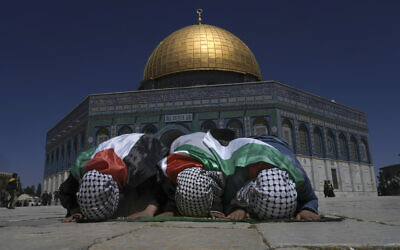 Muslim worshipers wrapped in Palestinian flags pray during holy Islamic month of Ramadan in front of the Dome of the Rock shrine at the Al Aqsa Mosque compound in Jerusalem's Old City, Friday, April 15, 2022. (AP/Mahmoud Illean)