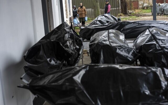 Nadiya Trubchaninova, 70, looks at the black bags containing the bodies of dead civilians, while she waits for her son's body to be delivered to the morgue so that she can have a decent burial in the cemetery of Mykulychi, on the outskirts of Kyiv, Ukraine, April 16, 2022. (AP Photo/Rodrigo Abd)