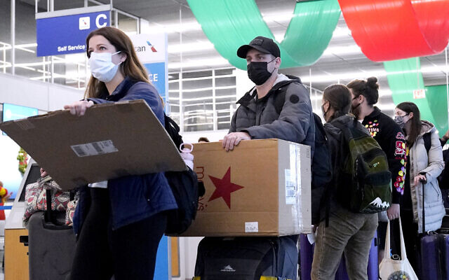 Travelers line up wearing protective masks indoors at O'Hare International Airport in Chicago, on December 28, 2021. (AP Photo/Nam Y. Huh, File)