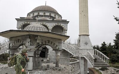 A serviceman of the Donetsk People's Republic militia walks past a damaged mosque during heavy fighting in an area controlled by Russian-backed separatist forces in Mariupol, Ukraine, on April 19, 2022. (AP Photo/Alexei Alexandrov)