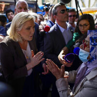 French far-right leader Marine Le Pen, left, talks to a woman as she campaigns in a market in Pertuis, southern France, on Friday, April 15, 2022. (AP/Daniel Cole, File)