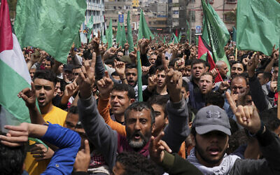 Hamas supporters wave green Islamic flags while raise their hands up and chant slogans during a rally in solidarity with Palestinian residents of the West Bank and Jerusalem, at the main road of Jebaliya refugee camp, northern Gaza Strip, April 22, 2022. (AP Photo/Adel Hana)