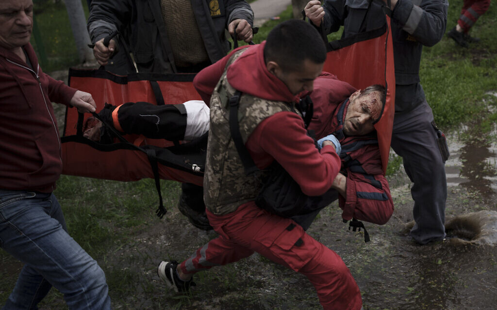 An emergency worker is helped by locals to carry a man to an ambulance following a Russian bombardment in Kharkiv, Ukraine, April 27, 2022. (AP Photo/Felipe Dana)