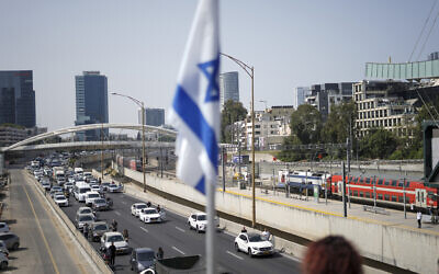 Israelis stand still next to their cars on a freeway as a two-minute siren sounds in memory of victims of the Holocaust in Tel Aviv, Israel, April 28, 2022 (AP Photo/Ariel Schalit)