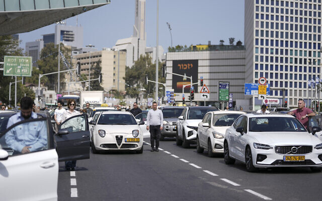 Israelis stand still next to their cars on a freeway as a two-minute siren sounds in memory of victims of the Holocaust in Tel Aviv, Israel, April 28, 2022 (AP Photo/Ariel Schalit)