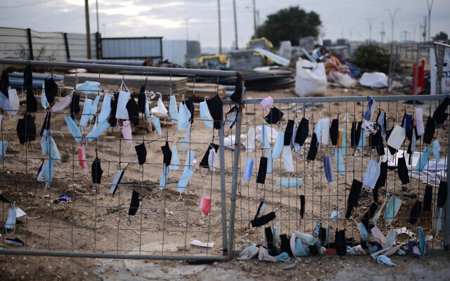 Face masks hang on a fence in Glilot, central Israel, on February 14, 2022. (Tomer Neuberg/Flash90)