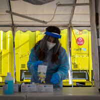 A Magen David worker takes a COVID-19 rapid antigen test from Israelis, at a Magen David Adom drive through complex in Jerusalem, on March 22, 2022.(Olivier Fitoussi/Flash90)