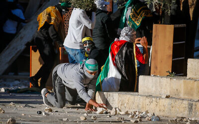 A Palestinian protester picks up a stone during clashes with Israeli police on the Temple Mount in Jerusalem's Old City on April 15, 2022. (Jamal Awad/Flash90)