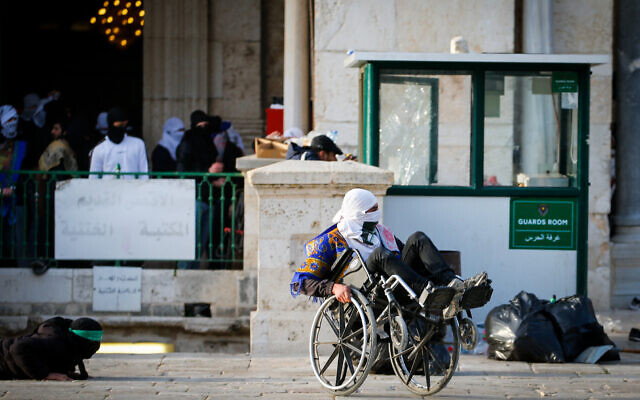 A masked Palestinian in a wheelchair takes part in clashes between Palestinians and Israeli police near Al-Aqsa Mosque at the Temple Mount in Jerusalem's Old City on April 22, 2022. (Jamal Awad/Flash90)