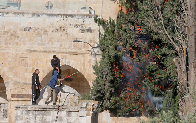 Palestinians try to put out a fire that broke out during clashes between Palestinians and Israeli police at the Temple Mount in Jerusalem's Old City on April 22, 2022. (Jamal Awad/Flash90)