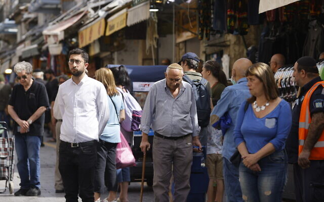 People stand still at Jerusalem's Mahane Yehuda market, as a two-minute siren is sounded across Israel to mark Holocaust Remembrance Day on April 28, 2022 (Olivier Fitoussi/Flash90)