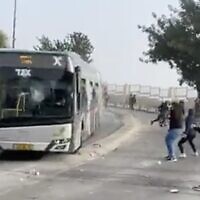 Palestinians throw rocks at an Israeli bus outside Jerusalem's Old City on April 17, 2022. (Screen capture: Twitter)