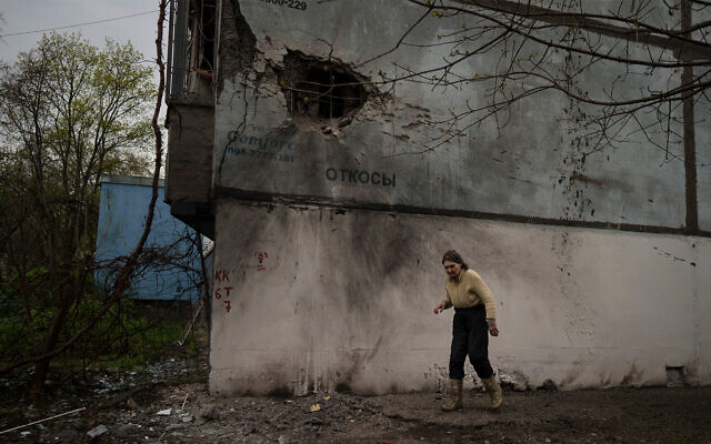 A woman walks next to a damaged building after a Russian bombardment in Kharkiv, Ukraine, on April 19, 2022. (AP Photo/Felipe Dana)