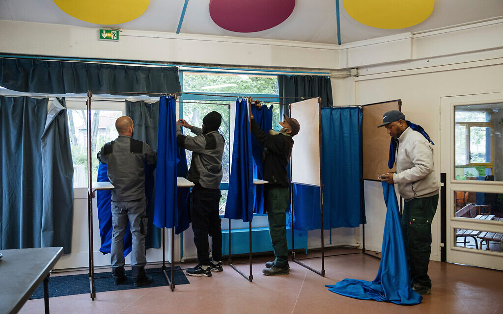 Municipality workers set up voting booths at a polling station in Montreuil, east of Paris, April 23, 2022. (AP Photo/Lewis Joly)