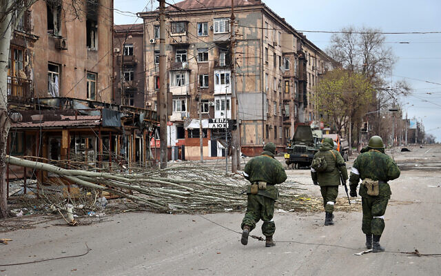Pro-Russia troops from the Donetsk People's Republic militia walk past damaged apartment buildings near the Illich Iron & Steel Works Metallurgical Plant in an area controlled by Russian-backed separatist forces in Mariupol, Ukraine, April 16, 2022. (AP Photo/Alexei Alexandrov)