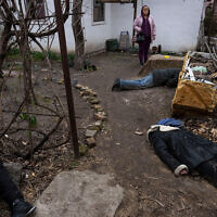 A woman stands next to three bodies in the courtyard of a house in Bucha, on the outskirts of Kyiv, Ukraine, on April 5, 2022. (AP Photo/Rodrigo Abd)