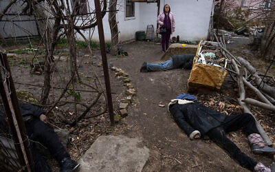 A woman stands next to three bodies in the courtyard of a house in Bucha, on the outskirts of Kyiv, Ukraine, on April 5, 2022. (AP Photo/Rodrigo Abd)