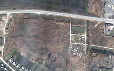 This photo, taken by Maxar Technologies' GeoEye-1 satellite on April 3, 2022, shows a newly excavated mass grave (the rows near the center top, just under the road) in the Ukrainian town of Manhush, which is close to the besieged port city Mariupol. (Satellite image ©2022 Maxar Technologies)