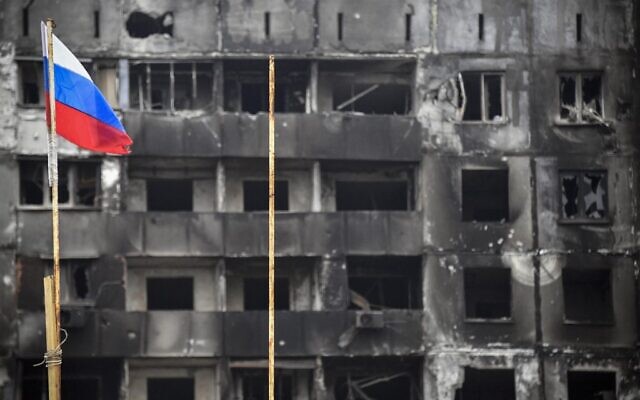 A Russian national flag flies by destroyed buildings in Mariupol on April 12, 2022. (Alexander NEMENOV / AFP)