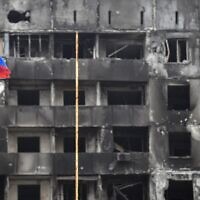 A Russian national flag flies by destroyed buildings in Mariupol on April 12, 2022, as Russian troops intensify a campaign to take the strategic port city. *EDITOR'S NOTE: This picture was taken during a trip organized by the Russian military.* (Photo by Alexander NEMENOV / AFP)