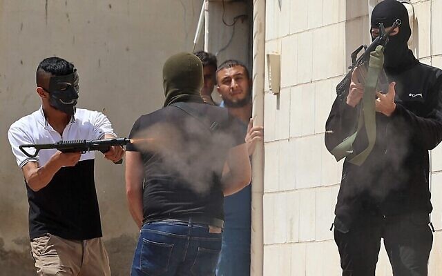 A masked Palestinian gunman fires an automatic weapon during clashes with Israeli security forces in the West Bank city of Jenin on May 13, 2022. (Jaafar Ashtiyeh/AFP)