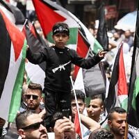 Palestinians wave national flags as they march in a rally marking the 74th anniversary of the 'Nakba' or 'catastrophe' of Israel's founding in the West Bank town of Ramallah, on May 15, 2022. (ABBAS MOMANI / AFP)