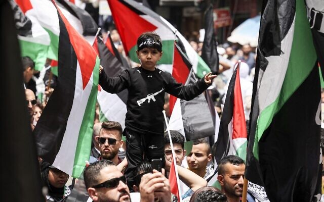 Palestinians wave national flags as they march in a rally marking the 74th anniversary of the 'Nakba' or 'catastrophe' of Israel's founding in the West Bank town of Ramallah, on May 15, 2022. (ABBAS MOMANI/AFP)