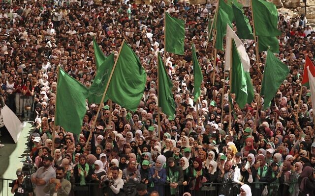 [Illustrative] Palestinian students supporting the Islamic Hamas movement wave national and movement flags as they attend a debate ahead of student council elections at Birzeit University on the outskirts of Ramallah in the West Bank, on May 17, 2022. (ABBAS MOMANI / AFP)