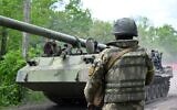 A Ukrainian serviceman looks at a self-propelled howitzer on a road in Kharkiv region on May 17, 2022. (SERGEY BOBOK / AFP)