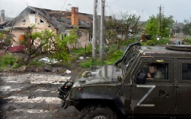A Russian military vehicle painted with the letter Z drives past destroyed houses in Ukraine's port city of Mariupol on May 18, 2022. (Olga MALTSEVA / AFP)