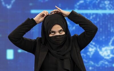 A female presenter for TOLOnews, Thamina Usmani, covers her face during a live broadcast at Tolo TV station in Kabul on May 22, 2022. (Wakil KOHSAR / AFP)