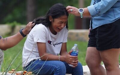 A girl cries, comforted by two adults, outside the Willie de Leon Civic Center where grief counseling will be offered in Uvalde, Texas, on May 24, 2022 (Allison Dinner / AFP)