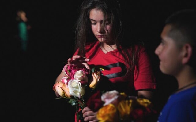 A young girl holds flowers outside the Willie de Leon Civic Center where people gather to mourn in Uvalde, Texas, May 24, 2022 (Allison Dinner / AFP)