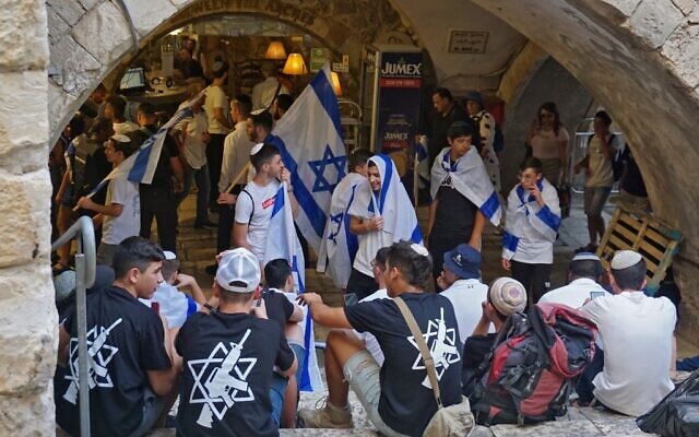 Young participants in a Jerusalem Day march wear t-shirts showing a Magen David and an assault rifle, in the Muslim Quarter of the Old City of Jerusalem on May 29, 2022, on "Jerusalem Day" (Claire GOUNON / AFP)