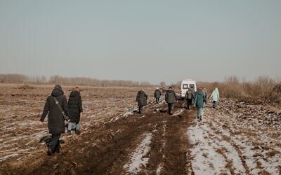 Civilians from the rescue convoy from Yaroslavka, Ukraine, walk on foot to lighten the loads of vehicles forced to travel through muddy fields, March 20, 2022. The roads were occupied by Russian soldiers. (Klara Lisinski/ Dorcas Kauffman)