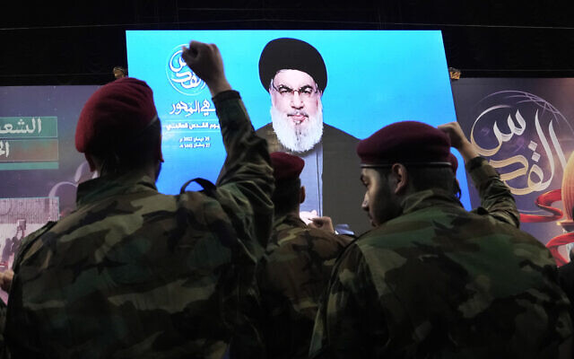 Hezbollah fighters raise their hands as their leader Sheik Hassan Nasrallah speaks via a video link during a rally in a southern suburb of Beirut, Lebanon, April 29, 2022. (Hassan Ammar/AP)