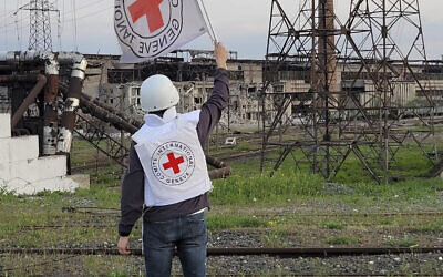 In this image provided by the International Committee of the Red Cross, a Red Cross official waves a white flag while approaching the Azovstal steelworks in Mariupol, Ukraine, Sunday, May 1, 2022.  (International Committee of the Red Cross via AP)