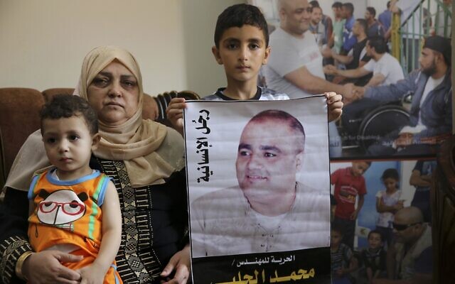 Amal el-Halabi (left) holds her grandson Fares while her grandson Amro, 7 (center) holds a picture of his father Mohammed el-Halabi, at their family home in Gaza city. The Arabic on the picture reads, " the man of humanity." August 8, 2016. (AP Photo/Adel Hana, File)