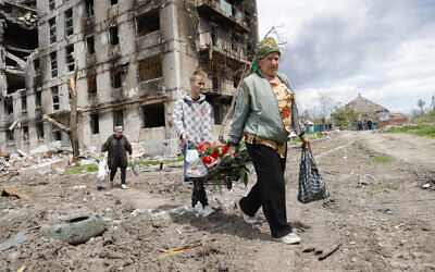 Women walk past a destroyed apartment building in Mariupol, in territory under the government of the Donetsk People's Republic, eastern Ukraine, Monday, May 2, 2022. (AP/Alexei Alexandrov)