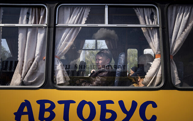 Women wait in a bus at a center for displaced people in Zaporizhzhia, Ukraine, Monday, May 2, 2022. The sign reads: "Bus." (AP Photo/Evgeniy Maloletka)