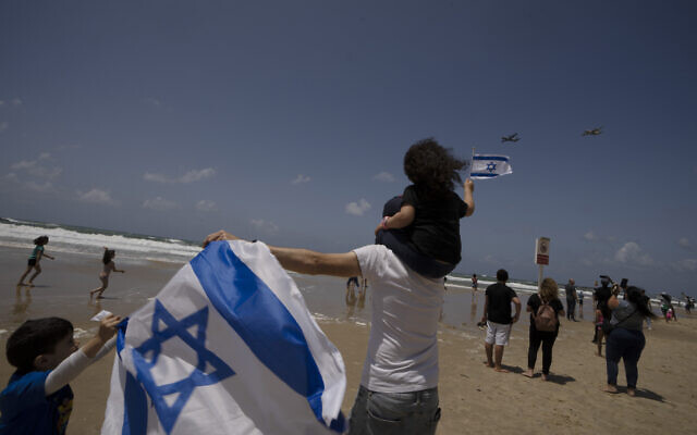 A family watches Israeli military cargo aircraft fly over Tel Aviv during the annual Independence Day flyover, May 5, 2022. (AP Photo/Maya Alleruzzo)