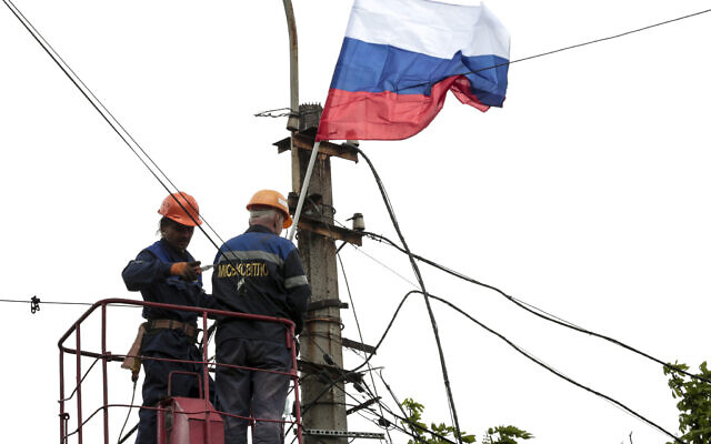Municipal workers attach a Russian national flag to a pole preparing to celebrate 77 years of the victory in WWII in Mariupol, in territory under the government of the Donetsk People's Republic, eastern Ukraine, Thursday, May 5, 2022. (AP)